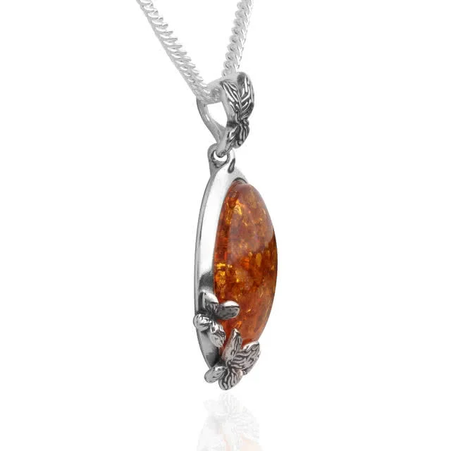 Finely detailed pendant features four oxidised butterflies resting on amber